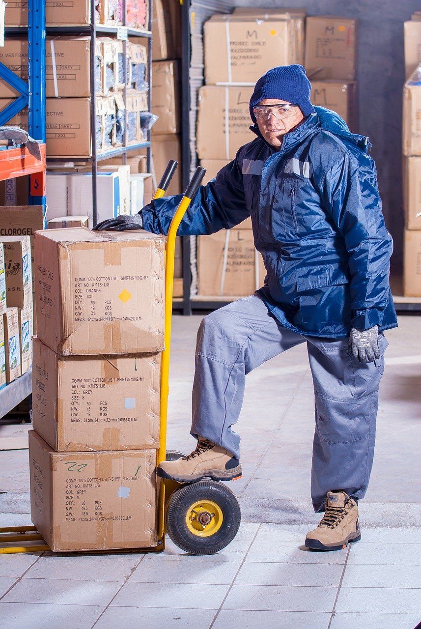 Delivery professional with a trolley of parcels at a warehouse